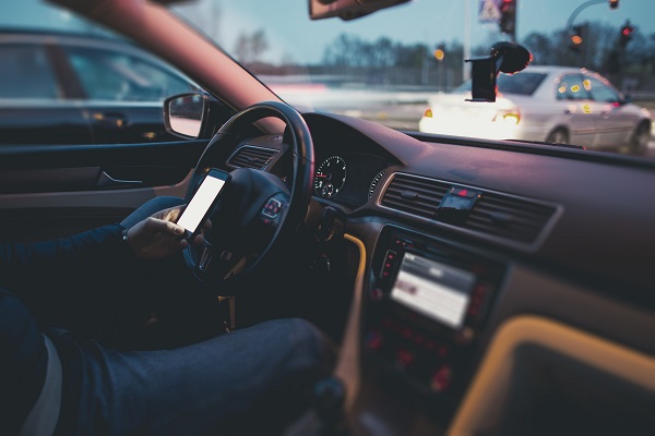 Texting while driving concept. A male driver browsing the internet and social media while behind the wheel of a car.