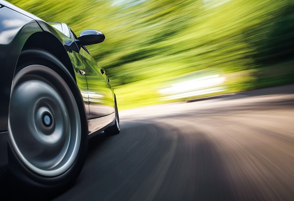 Front side view of black luxury sedan in turn, speeding.