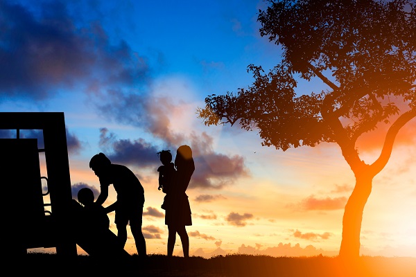 Silhouette family of a mother, father, son, and daughter playing outside at sunset.