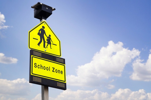 School zone traffic sign against a blue sky background.